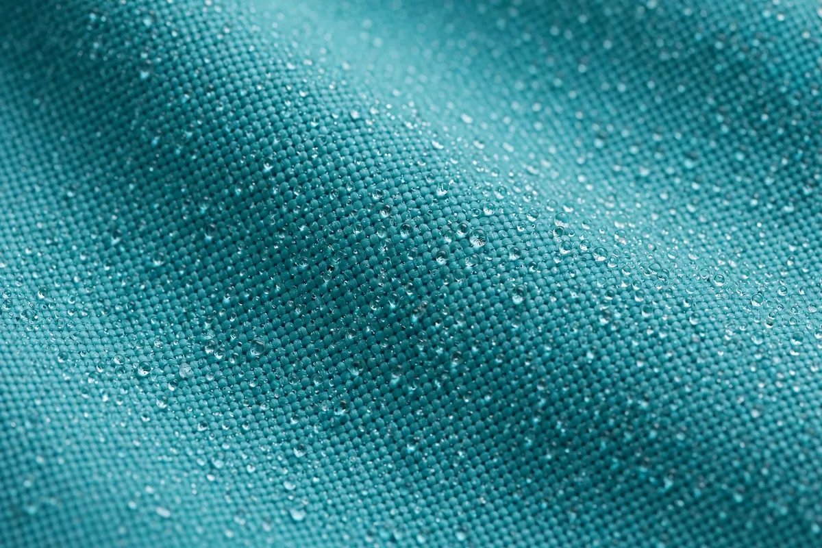 Macro view of teal quick-dry swim fabric with water droplets beading on the woven surface